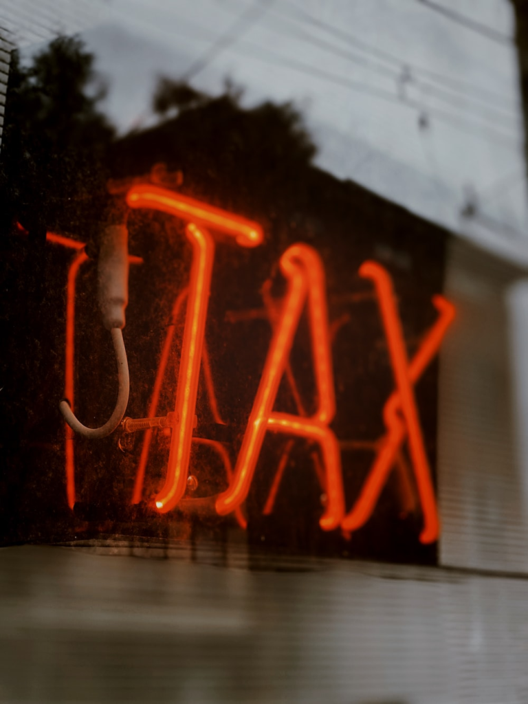 a red neon light saying tax.