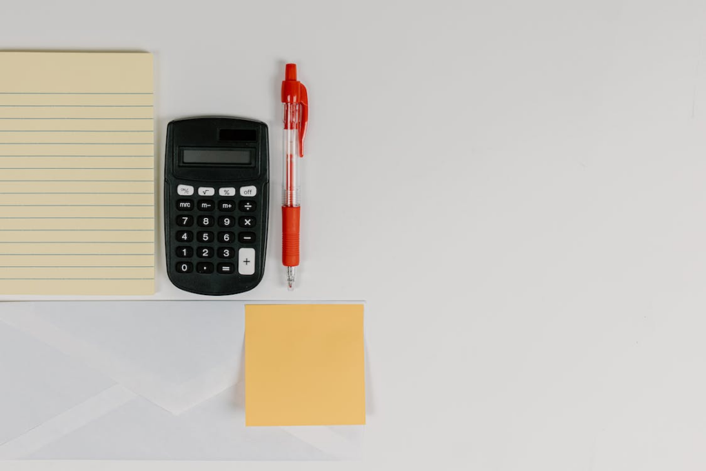 An image of a black calculator beside a pen 