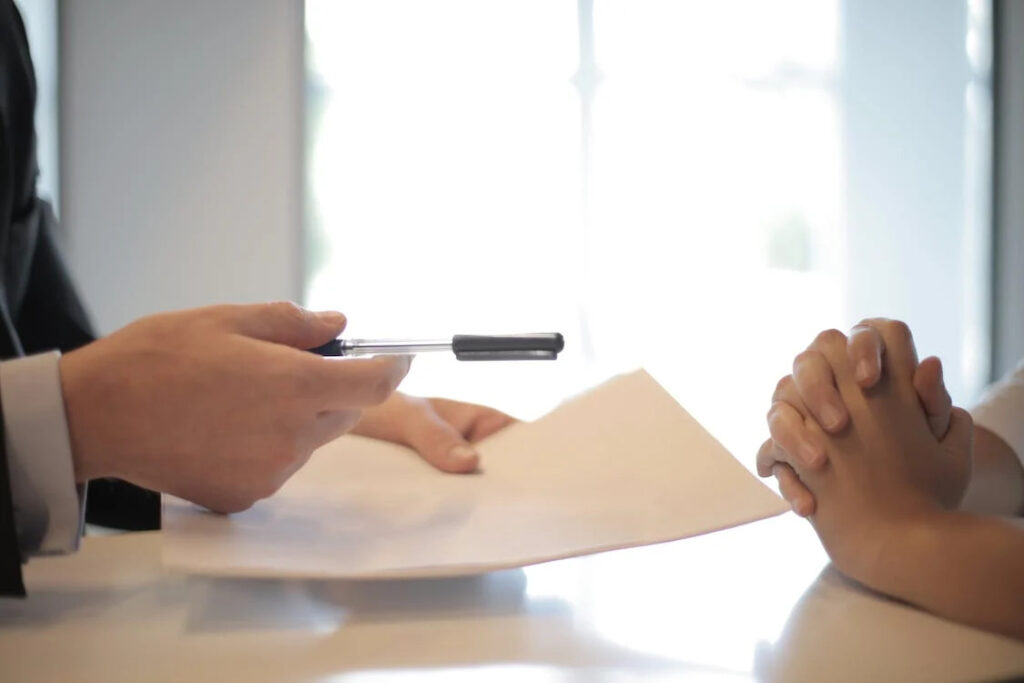 An image of a man giving a contract to a woman for signing 