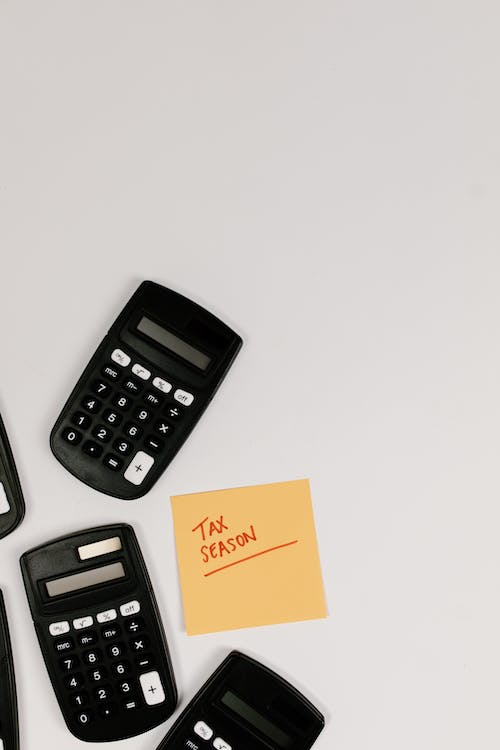 An image of black calculators on a white surface with a sticky note
